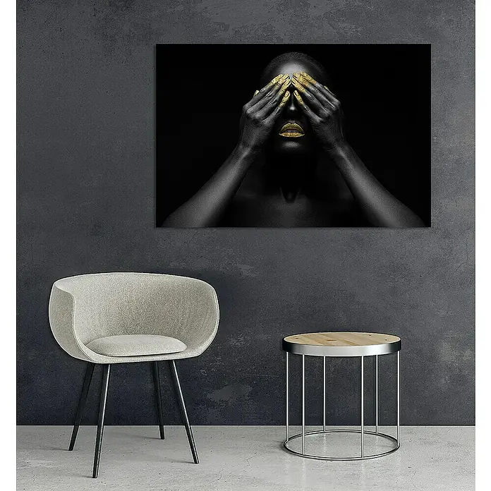 Glasbild - Frau Gold, B x H: 90 x 60 cm - Wandbild mit einer Frau in Schwarz und Gold, stilvoll über einem Stuhl und einem Beistelltisch platziert, verleiht dem Raum eine elegante Note.