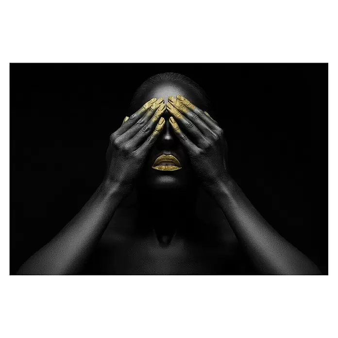 Glasbild - Frau Gold, B x H: 90 x 60 cm - Person mit schwarzer Körperfarbe, goldenen Lippen und goldbemalten Händen, die die Augen bedecken.