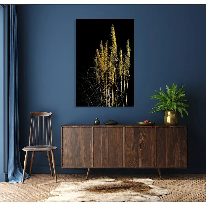 Glasbild - Pampagras, B x H: 30 x 40 cm - Das Bild zeigt ein abstraktes Kunstwerk mit goldenen Schilfhalmen vor einem tiefschwarzen Hintergrund, das über einer Holzkommode hängt.