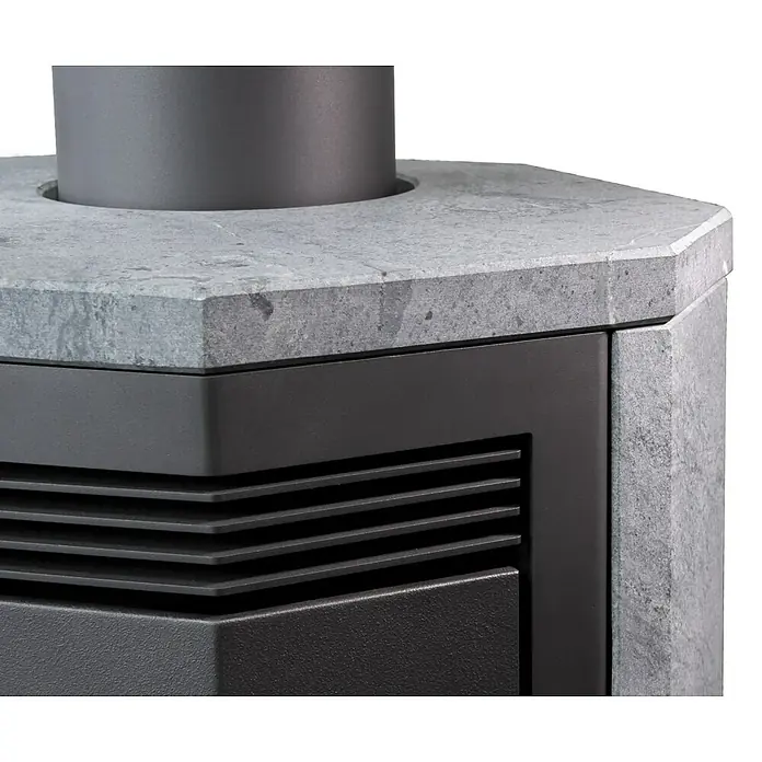 Justus Kaminofen Usedom 5 II - 5,5 kW, Raumheizvermögen: 88 m³, Material Verkleidung: Stahl, Schwarz - Nahaufnahme eines Ofens mit grauer Steinplatte, Lüftungsschlitzen und einem schwarzen Metallrahmen.