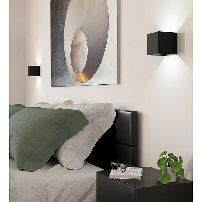Eglo LED-Wandleuchte Valmontone - 1,5 W, L x B x H: 10 x 10 x 10 cm, Schwarz, Warmweiß - Schlafzimmer-Szene mit zwei schwarzen würfelförmigen Wandleuchten, die ein warmes Licht ausstrahlen und eine moderne und gemütliche Atmosphäre schaffen.