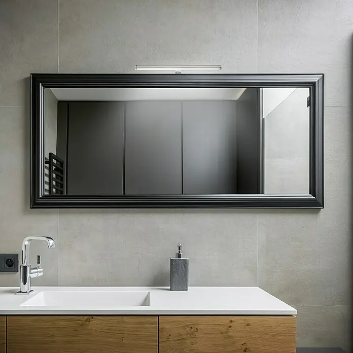 Briloner Aplique LED para espejo - L x An x Al: 40 x 9 x 4 cm, IP44 - Un espejo rectangular con marco negro y luz cuelga sobre un lavabo con piso de madera y grifo en un baño moderno.