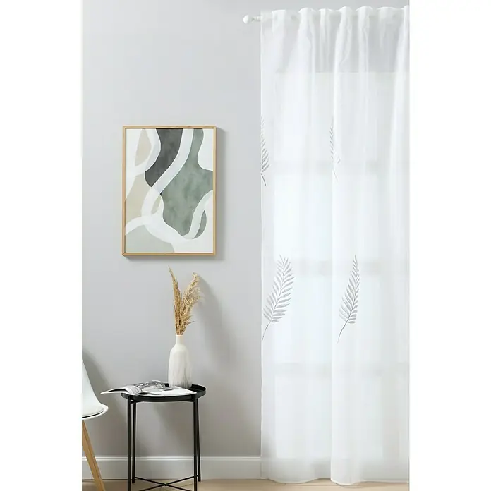 Visillo para ventana Palma - An x Al: 140 x 280 cm, 100% poliéster, Blanco - Una cortina transparente con delicados estampados de hojas, complementada con una decoración minimalista que incluye una obra de arte y una mesa auxiliar.