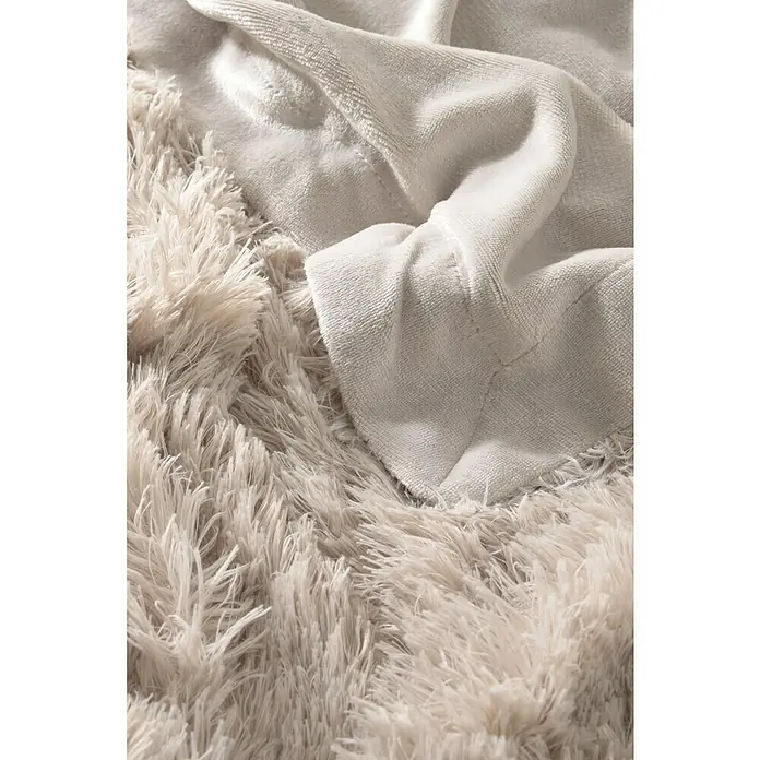 Manta para sofá New Luxury - 160 x 220 cm, Poliéster, Beige - Primer plano de una manta beige peluda y una manta lisa apiladas, que ofrecen calidez y comodidad.