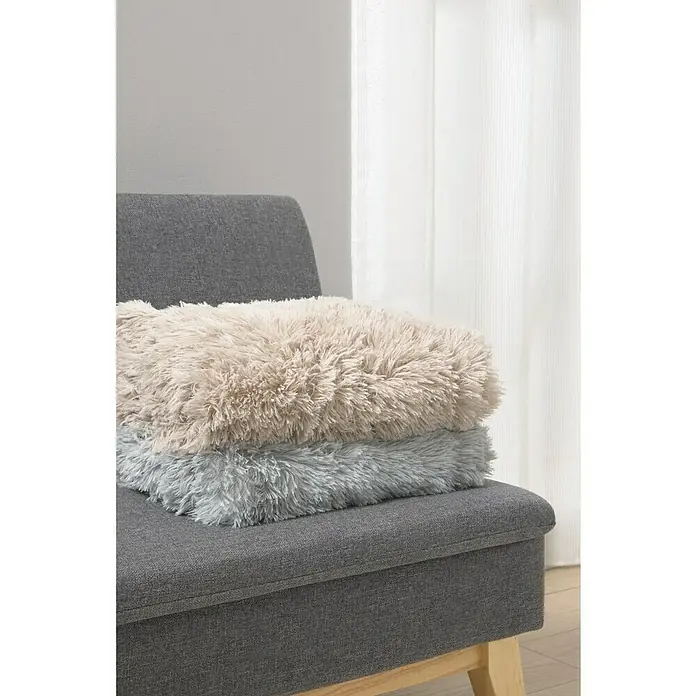 Manta para sofá New Luxury - 160 x 220 cm, Poliéster, Beige - Una silla gris con dos cojines esponjosos en beige y gris encima. Estos cojines invitan a relajarse con comodidad.