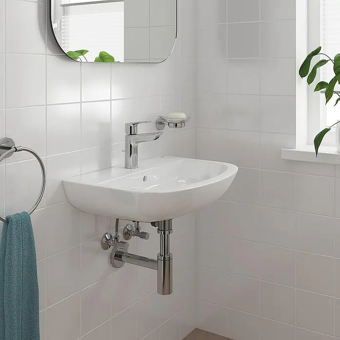 Grohe QuickFix Start Loop Grifo de lavabo M - Cromo, Brillante - Primer plano de un lavabo blanco con grifo y toallero en un baño con azulejos blancos.
