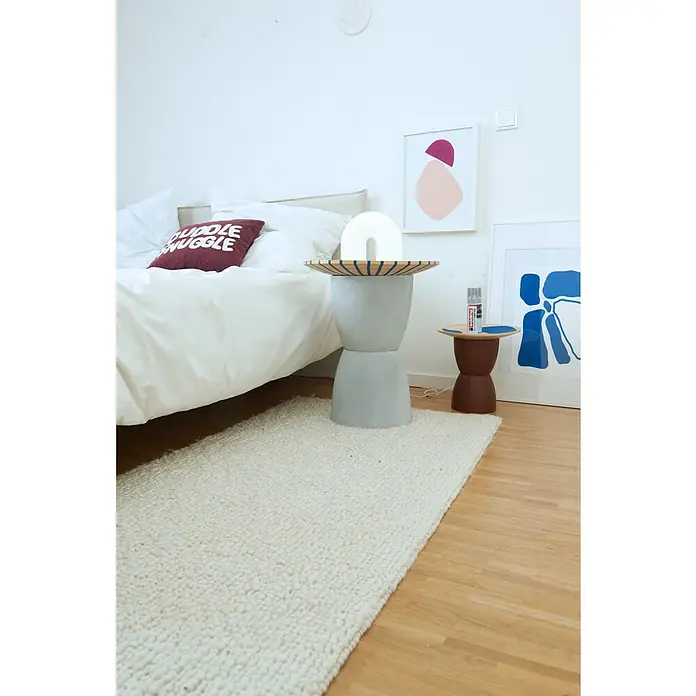 Edding Sprühlack Effekt - Beton Effekt, Seidenmatt, 200 ml - Nahaufnahme eines stilvollen Schlafzimmers mit einem Akzentteppich und Beistelltischen mit Dekor.
