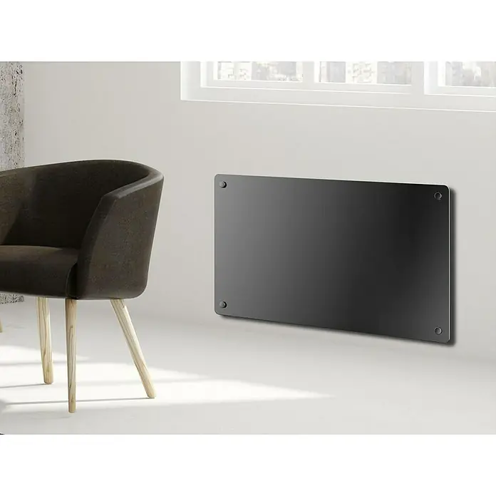Purline Emisor térmico de cristal - An x Al: 70 x 40 cm, 1.500 W - Un elegante panel calefactor negro montado en la pared junto a una silla moderna, que añade calidez y un diseño moderno a la habitación.