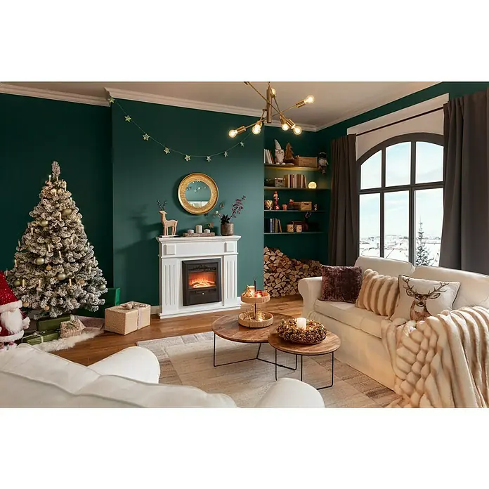 SCHÖNER WOHNEN-Farbe Wandfarbe DesignfarbeBesinnliches Waldgrün, Matt, 1 l, Konservierungsmittelfrei - Gemütliches Wohnzimmer mit Kamin, Weihnachtsbaum und Dekorationen. Die sanfte Beleuchtung schafft eine festliche Atmosphäre im Raum.