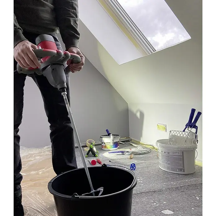 Berg Tecmix Handrührwerk TMX PRO 1600 - Durchmesser Rührer: 160 mm, Leistungsaufnahme: 1.600 W - Ein Mann mischt Farbe mit einem Farbmischer in einem Eimer. Der Mischer ist rot und grau und befindet sich in einem schwarzen Eimer.