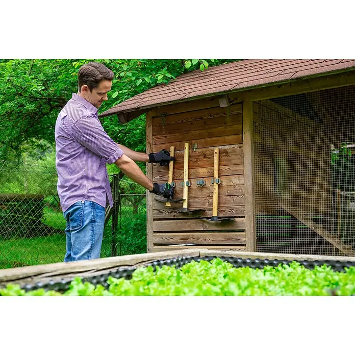 Freund Victoria Gerätehalter Universal - Geeignet für: Stiel-Durchmesser von 20-30 mm - Ein Mann hängt Gartengeräte an einem Holzschuppen auf. Praktische Aufbewahrung für Spaten und Hacke im Garten.