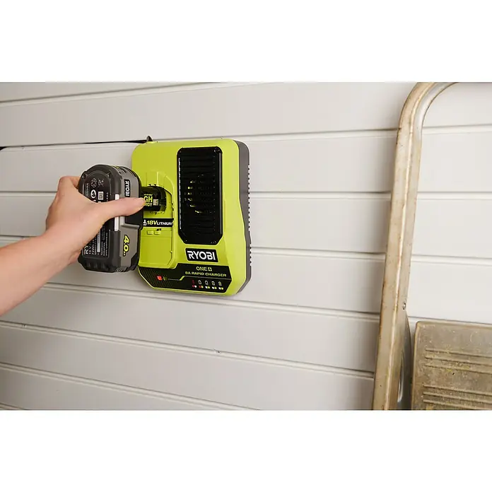 Ryobi ONE+ Akku-Schnellladegerät RC18180 - Passend für: Ryobi One+ 18V Akkus - Nahaufnahme eines Ryobi ONE+ 18V Akku-Ladegeräts mit eingesetztem Akku an einer Wand montiert.