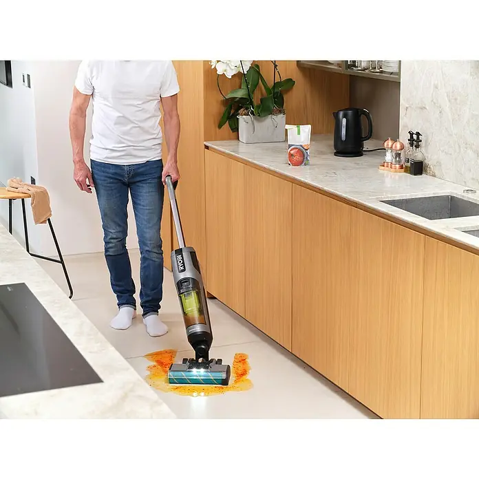 Ryobi ONE+ Akku-Hartbodenreiniger RHFC18BL-0 - 18 V, Ohne Akku, Luftmenge: 710 l/min - Eine Person benutzt einen RYOBI Akku-Nass-Trockensauger, um eine verschmutzte Küchenoberfläche zu reinigen. Das Gerät ist kompakt und benutzerfreundlich.
