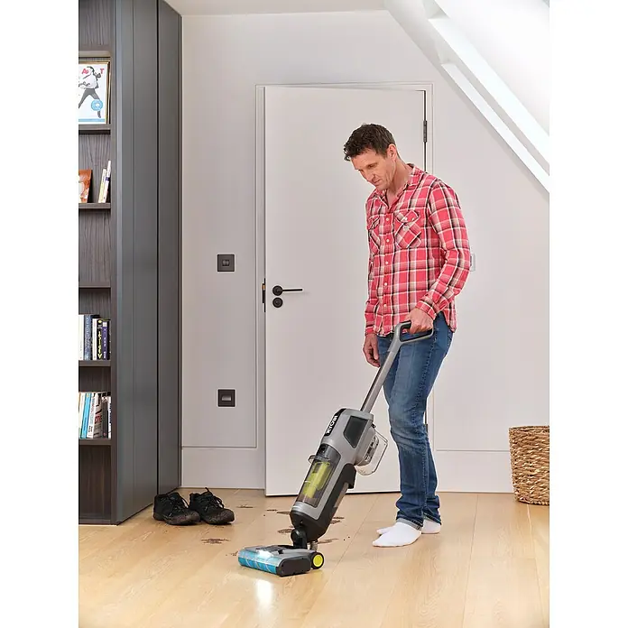 Ryobi ONE+ Akku-Hartbodenreiniger RHFC18BL-0 - 18 V, Ohne Akku, Luftmenge: 710 l/min - Ein Mann benutzt einen RYOBI Akku-Nass-Trockensauger, um Schmutz auf einem Holzboden zu entfernen. Praktische Reinigungslösung für den Haushalt.