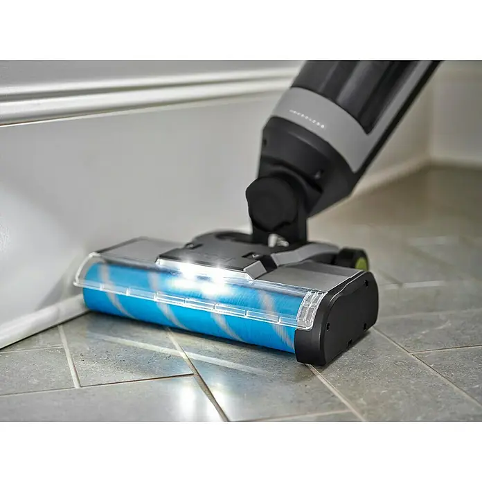 Ryobi ONE+ Akku-Hartbodenreiniger RHFC18BL-0 - 18 V, Ohne Akku, Luftmenge: 710 l/min - Nahaufnahme eines Bodenreinigers mit blau-weisser Bürste, der auf Fliesen entlang einer Wand verwendet wird.