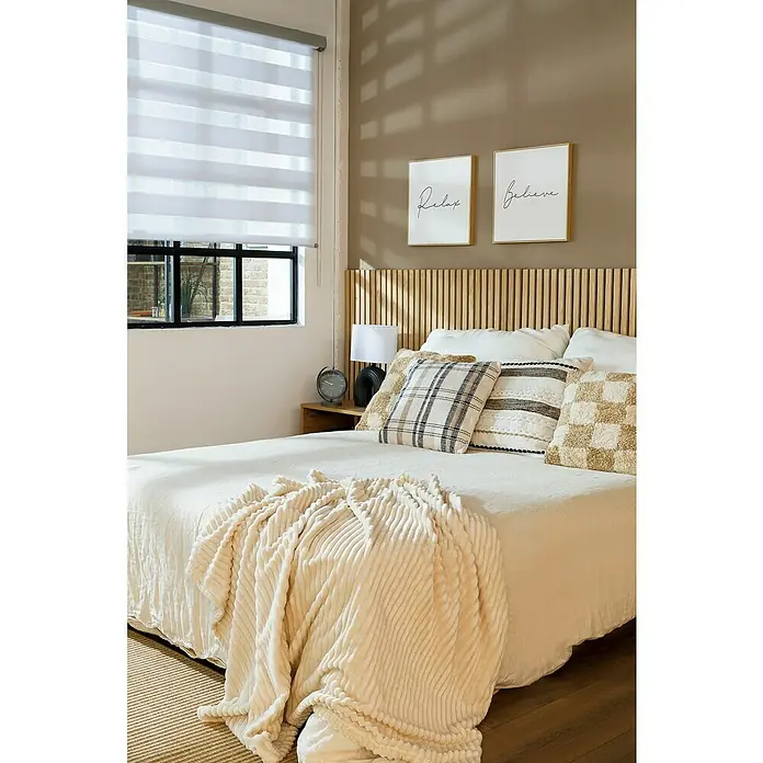 Alfombra exterior pasillero In&Out Natural - Natural, 200 x 50 cm, Polipropileno - Primer plano de una cama acogedora con una manta suave y cojines decorativos delante de un cabecero de madera.
