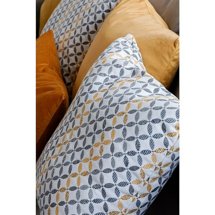 Cojín Velvet - 45 x 45 cm, Textil, Yema - Varios cojines decorativos en tonos amarillos y grises con patrones geométricos, colocados en un sofá o cama.