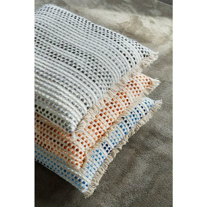 Cojín Dakira - 45 x 45 cm, Textil, Natural, Cuadrado - Primer plano de cojines apilados y texturizados con flecos, sentados sobre una alfombra, creando un ambiente acogedor.