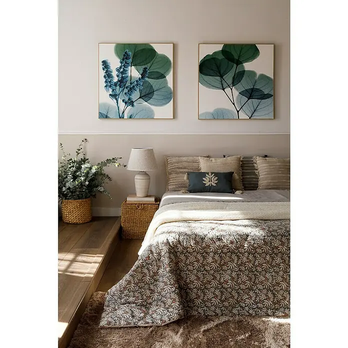 Nmc Decoflair Zierprofil Wandleiste CL2 - 2 Stk., 2 m x 13 mm x 25 mm, Hochverdichtetes extrudiertes Polymer (HDPS) - Ein Schlafzimmer mit zwei botanischen Wandkunstwerken über einem Bett mit gemusterter Tagesdecke und dekorativen Kissen.