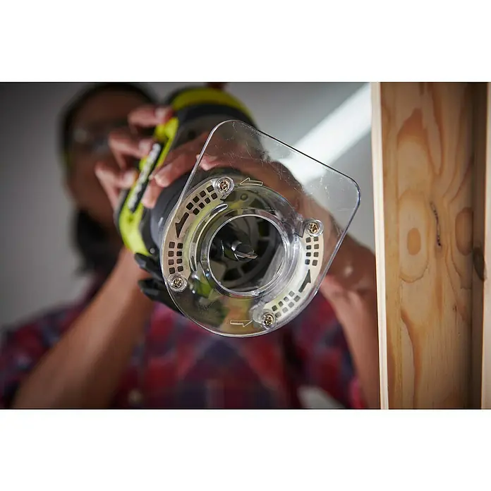 Ryobi ONE+HP Akku-Kantenfräser RTR18C-0 - 18 V, Ohne Akku - Nahaufnahme einer Oberfräse mit Schutzvorrichtung, die von einer Person an einem Holzstück bedient wird. Präzision und Sicherheit im Fokus.