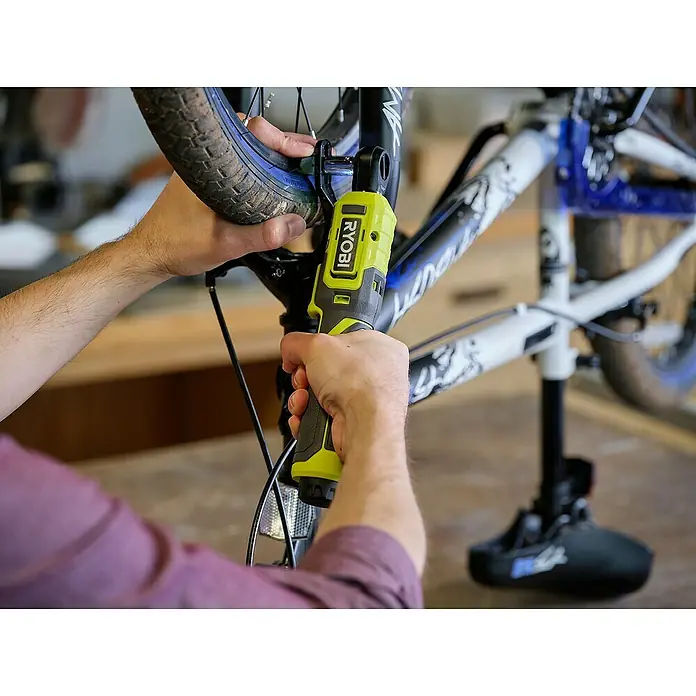 Ryobi 4V USB Akku-Ratschenschrauber RR14W4-0 - 4 V, Ohne Akku - Nahaufnahme einer Person, die mit einem Ryobi-Elektrowerkzeug an einem Fahrrad arbeitet, das auf einem Montageständer steht.
