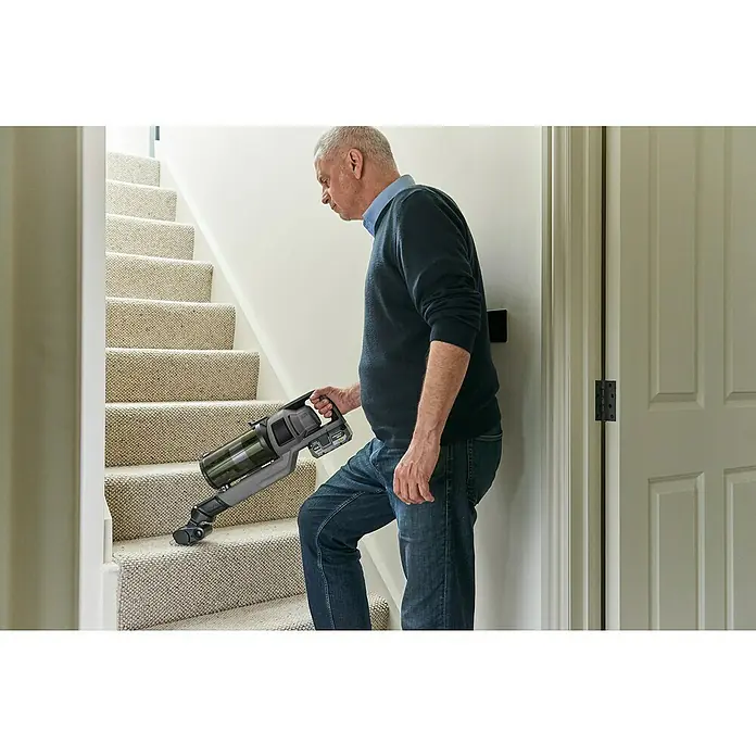 Ryobi ONE+ Akku-Staubsauger RSV18BL - 18 V, 1 Akku, 4 Ah, Behältervolumen: 0,8 l - Ein Mann staubsaugt eine Treppe mit einem kabellosen Handstaubsauger, der leicht und einfach zu bedienen ist.
