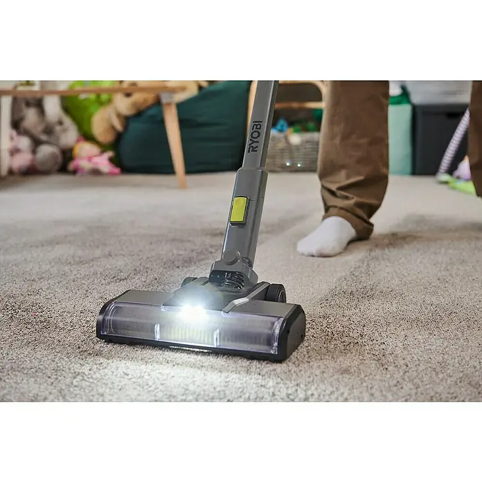 Ryobi ONE+ Akku-Staubsauger RSVS18BL-0 - 18 V, Ohne Akku, Behältervolumen: 0,8 l - Nahaufnahme eines Ryobi Akku-Staubsaugers mit eingeschaltetem Licht beim Staubsaugen eines Teppichs.