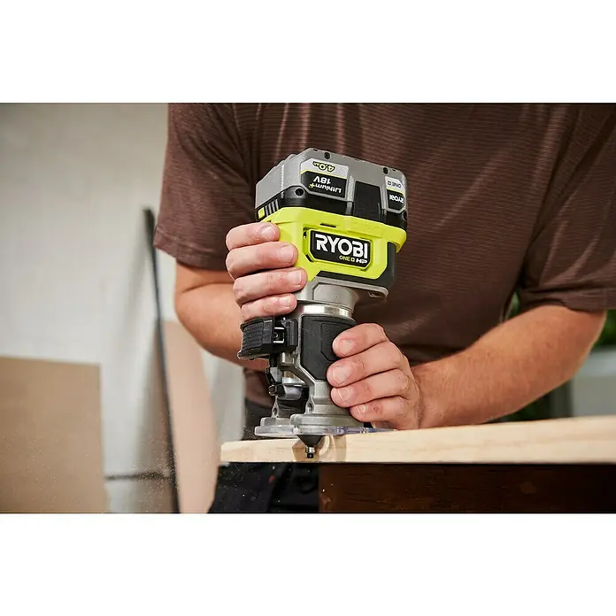 Ryobi ONE+HP Akku-Kantenfräser RTR18C-0 - 18 V, Ohne Akku - Nahaufnahme eines Ryobi ONE+ Akku-Trimmers im Einsatz an einem Holzstück, der sich ideal für präzise Holzarbeiten eignet.