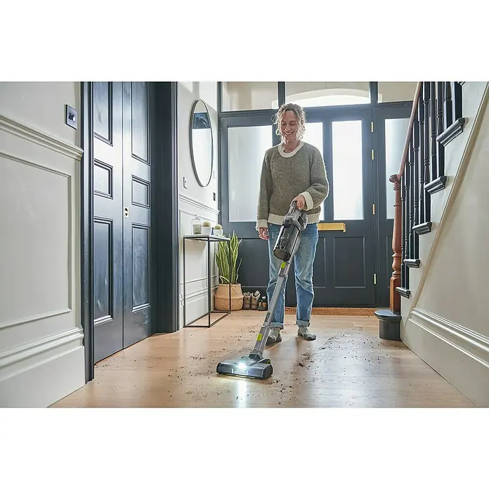 Ryobi ONE+ Akku-Staubsauger RSV18BL - 18 V, 1 Akku, 4 Ah, Behältervolumen: 0,8 l - Frau saugt mit einem Ryobi Akku-Staubsauger den Flur. Der kabellose Staubsauger beseitigt mühelos Schmutz von Holzböden.