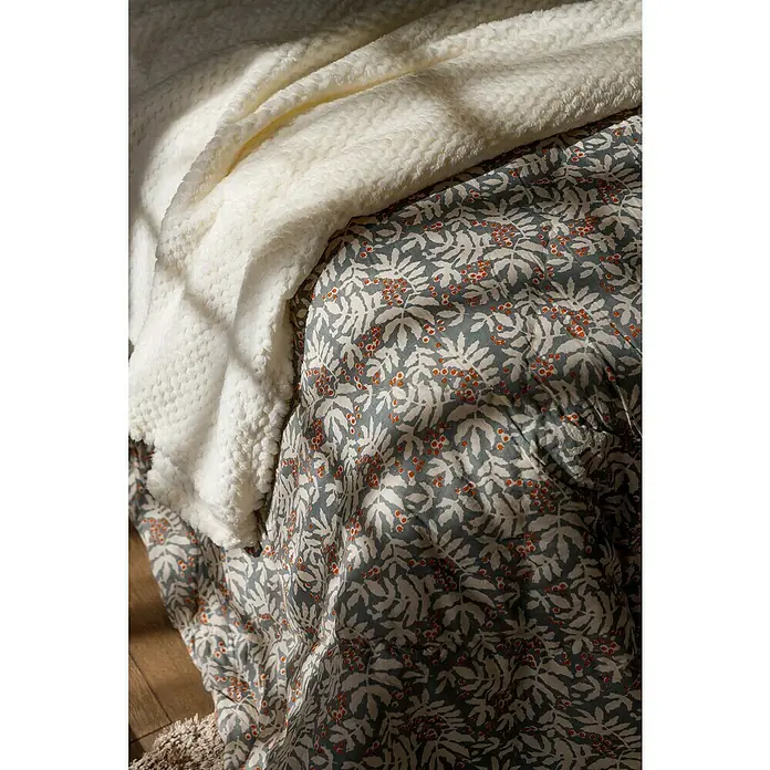 Manta para sofá Otoño - Textil, Azul/Crudo - Primer plano de una manta sherpa blanca y suave y de un cubrecama acolchado con un estampado de hojas y bayas para mayor comodidad.