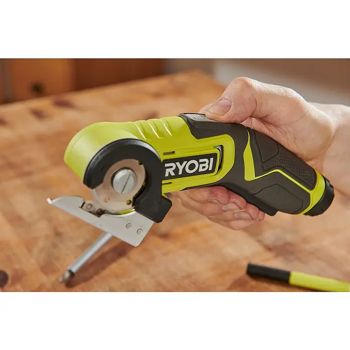 Ryobi 4V USB Akku-Universalschere RCT4-0 - 4 V, Ohne Akku - Eine Nahaufnahme einer Ryobi-Rotationsschneidemaschine, die von einer Hand gehalten wird, mit einem Holztisch im Hintergrund.