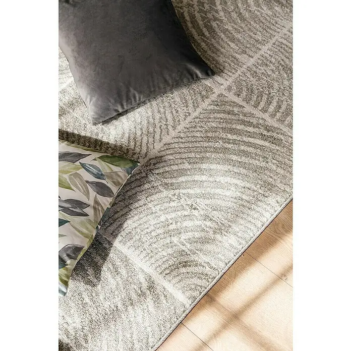 Cojín Velvet - 45 x 45 cm, Textil, Gris - Primer plano de una alfombra estampada con dos cojines. La alfombra tiene un diseño abstracto y gris y está sobre un suelo de madera.