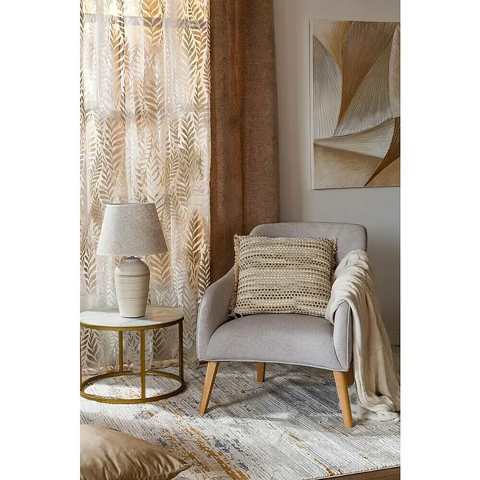 Cojín Velvet - 45 x 45 cm, Textil, Topo - Escena interior con un sillón gris claro con cojín, una mesa auxiliar con una lámpara y una obra de arte abstracta en la pared.