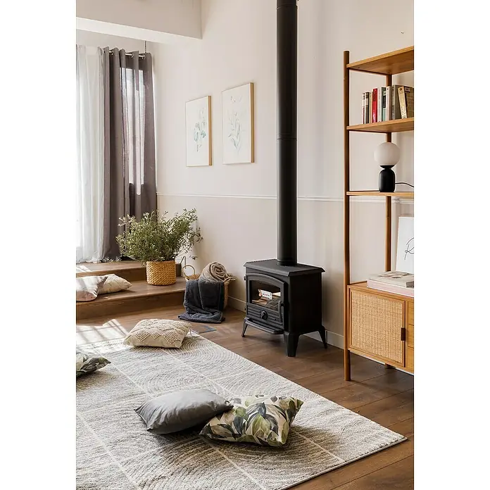 Visillo para ventana Selena - An x Al: 140 x 260 cm, 100% poliéster, Gris/Blanco - Acogedora sala de estar con estufa de leña negra, que aporta calidez y estilo. La alfombra clara y los cojines decorativos crean un espacio acogedor.