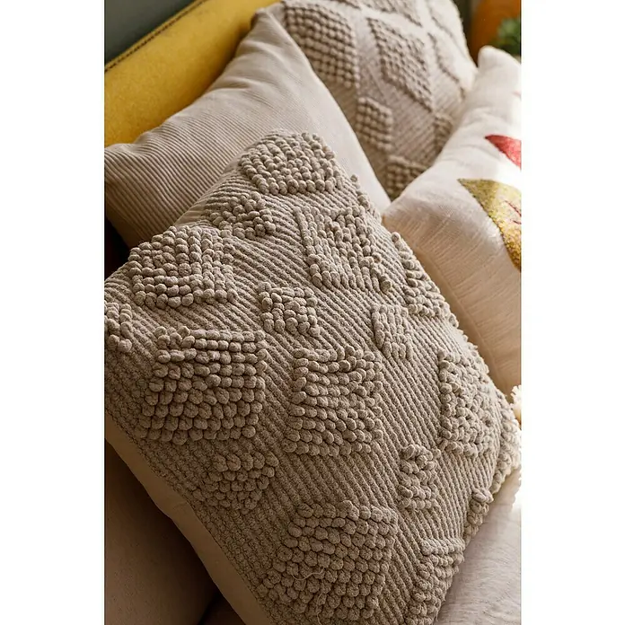 Cojín Pana - 45 x 45 cm, Poliéster, Crudo, Cuadrado - Primer plano de cojines decorativos con diversas texturas y patrones en un sofá.