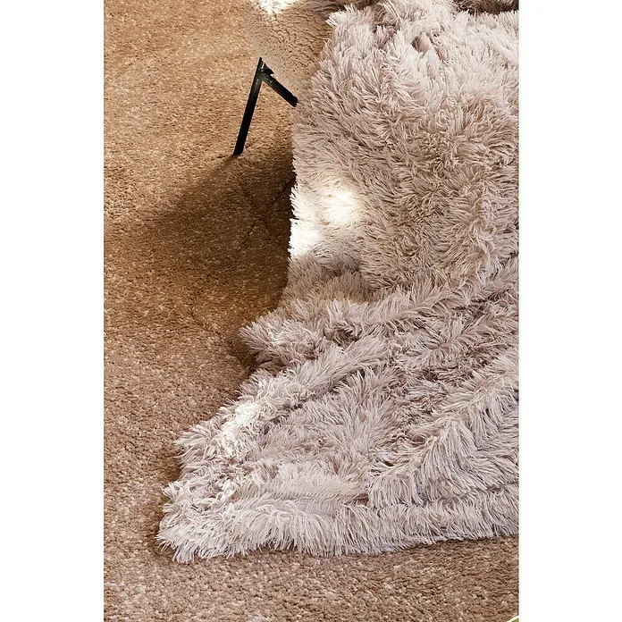 Manta para sofá New Luxury - 160 x 220 cm, Poliéster, Beige - Primer plano de una alfombra shaggy de color claro y esponjosa que se encuentra sobre una alfombra marrón, creando un ambiente acogedor.