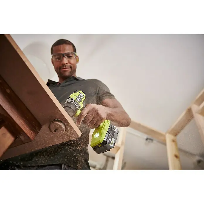 Ryobi ONE+HP Akku-Bohrschrauber RDD18C1-0 C - 18 V, Ohne Akku, 60 Nm - Ein Mann benutzt einen gelben Ryobi Akku-Bohrschrauber, um Holz zu bearbeiten. Das Werkzeug ist ein zentrales Element der Szene.