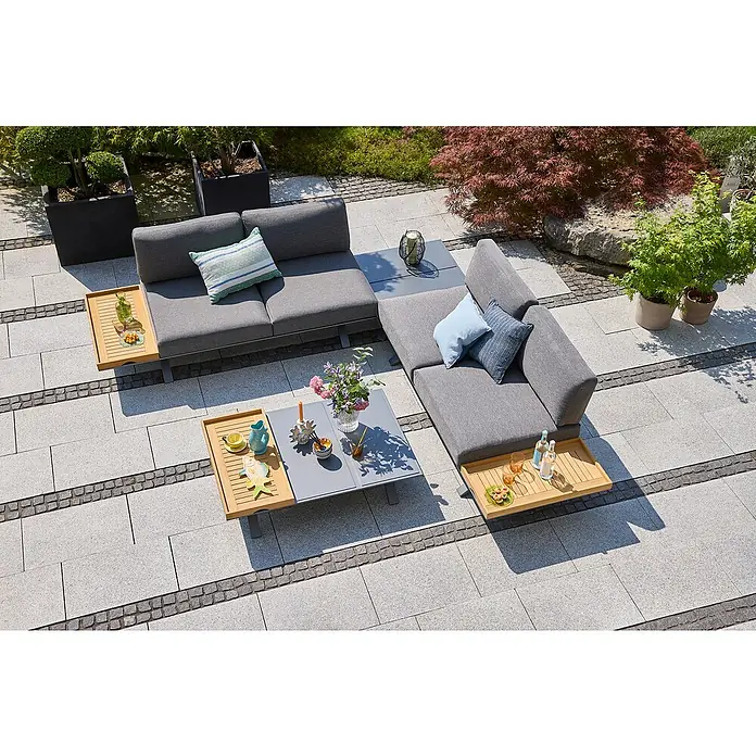 Sunfun Loungemöbel-Set Lumar II - 7 -tlg., Aluminium, Teak, Tisch groß, Night-Grey - Eine stilvolle graue Gartenmöbel-Lounge-Set-Anordnung mit Couchtischen und dekorativen Accessoires im Freien auf einer gepflasterten Terrasse.
