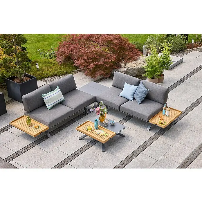 Sunfun Lumar Loungesofa - L x B x H: 195,5 x 87 x 68 cm, Aluminium, Night-Grey - Graue Gartenmöbel mit Holztischplatten und bunten Kissen inmitten eines üppigen Gartens mit Bäumen und Pflanzen.