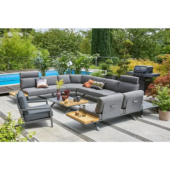 Sunfun Lumar Loungesofa-Eckelement - L x B x H: 115 x 115 x 68 cm, Aluminium, Night-Grey - Eine graue Gartenlounge-Gruppe mit Tisch und Grill auf einer Terrasse, umgeben von üppigem Grün und einem Pool.