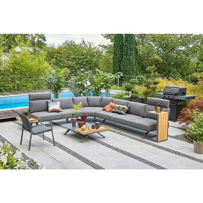 Sunfun Loungemöbel-Set Lumar/Solo - 10 -tlg., Aluminium, Teak, Night-Grey - Eine graue Gartenlounge-Gruppe mit Beistelltisch und Grill auf einer gepflasterten Terrasse neben einem Pool, umgeben von üppigem Grün.