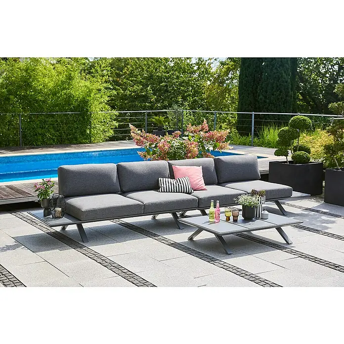 Sunfun Loungemöbel-Set Lumar - 3 -tlg., Aluminium, Night-Grey - Ein graues Gartensofa mit Couchtisch und dekorativen Elementen, umgeben von Grünpflanzen und einem Pool.
