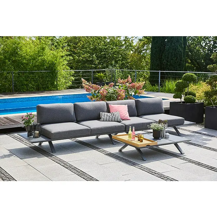 Sunfun Loungemöbel-Set Lumar - 4 -tlg., Aluminium, Teak, Ablagefläche links und rechts, Night-Grey - Eine graue Outdoor-Couchgarnitur mit Beistelltisch und Couchtisch auf einer Terrasse. Im Hintergrund ein Pool und Pflanzen.