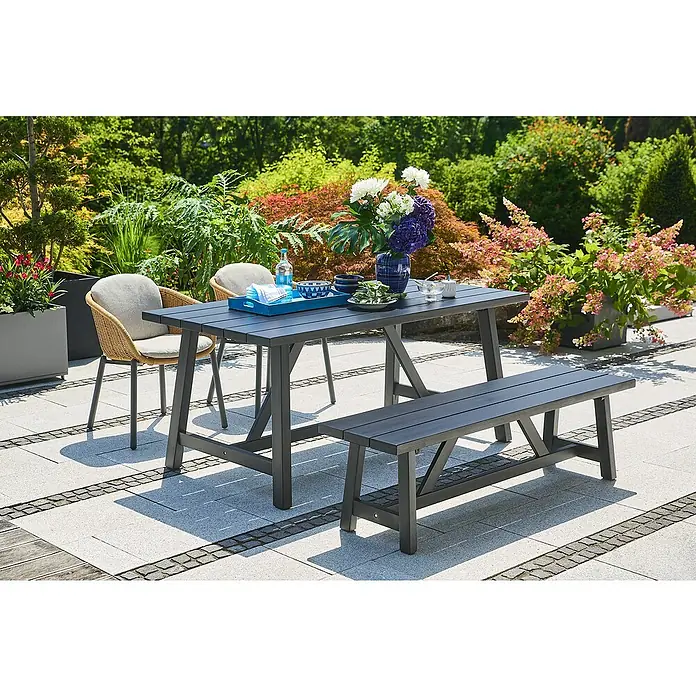 Sunfun Gartenmöbel-Set Melina - 4 -tlg., Akazie/Aluminium/Polyester, Black Washed/Braun - Gartenmöbelset mit Tisch, Bank und Stühlen auf einer Terrasse, umgeben von üppigem Grün.