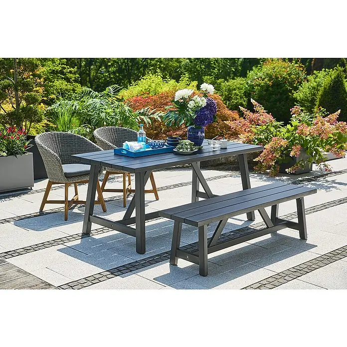 Sunfun Gartenmöbel-Set Melina/Pauline - 4 -tlg., Akazie/Polyrattan/Aluminium, Black Washed/Bambus Grey/Natur - Gartenszene mit einem Esstisch aus Holz und einer passenden Bank. Der Tisch ist mit Geschirr und Blumen dekoriert.