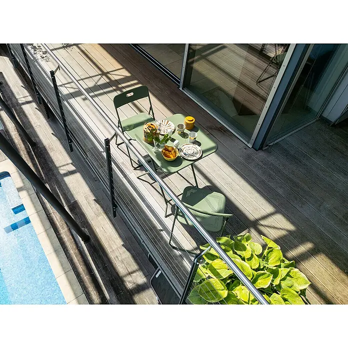 Balkonmöbel-Set Jordan - 3 -tlg., Grün, Klappbar - Ein grüner Gartentisch und zwei Stühle stehen auf einer Terrasse, bereit für eine Mahlzeit im Freien. Das Set bietet einen gemütlichen Platz zum Entspannen.