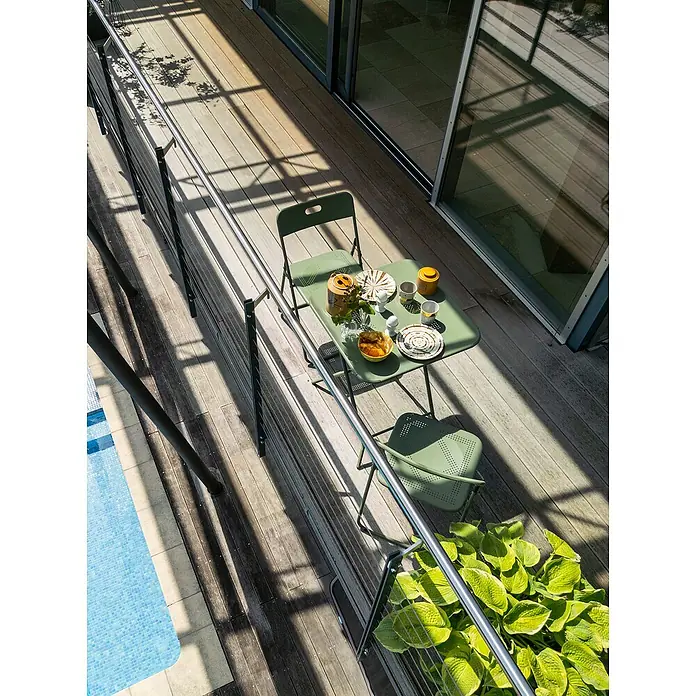Balkonmöbel-Set Jordan - 3 -tlg., Grün, Klappbar - Gartentisch mit Geschirr und Stühlen auf einer Terrasse mit Pool. Die grünen Gartenmöbel laden zum Verweilen ein.