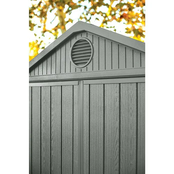 Keter Gartenhaus Darwin 6x4 - Außenmaß inkl. Dachüberstand (B x T): 190 x 122 cm, Kunststoff, Grün, 2,3 m² - Nahaufnahme eines Gartenhauses mit grauem Holzstrukturmuster, einem Giebeldach und einem runden Lüftungsgitter unter dem Dachfirst.