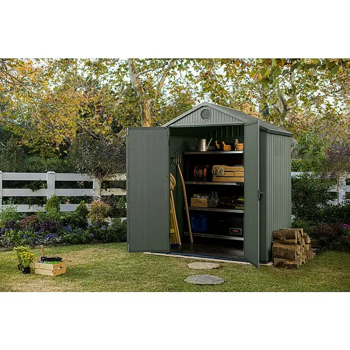 Keter Gartenhaus Darwin 6x4 - Außenmaß inkl. Dachüberstand (B x T): 190 x 122 cm, Kunststoff, Grün, 2,3 m² - Aufnahme eines Metallgartenschuppens mit Regalen, in denen Gartengeräte und Zubehör aufbewahrt werden, im Freien.