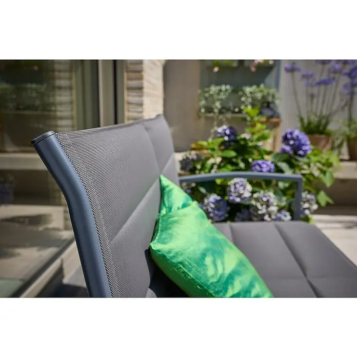 Loungemöbel-Set - 4 -tlg., Metall/Textil, Schwarz/Grau - Nahaufnahme eines modernen Gartenstuhls mit grauem Bezug und grünem Kissen, umgeben von üppigen Pflanzen.